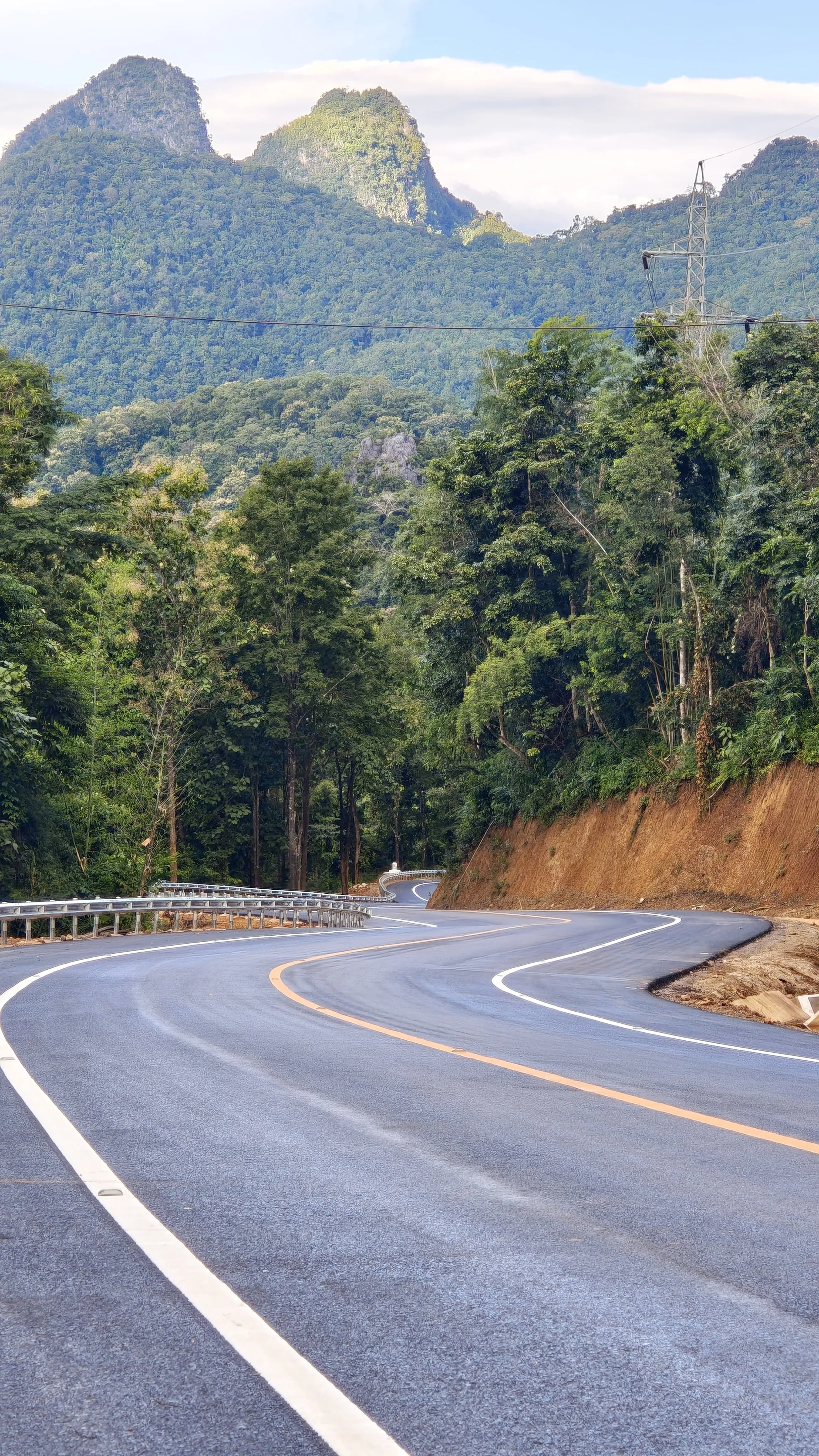 Carretera recién asfaltada con curvas. Imagen al fondo de una montaña